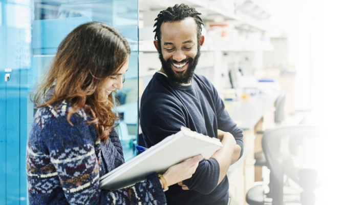 Un homme et une femme heureux de collaborer autour d’un bloc note