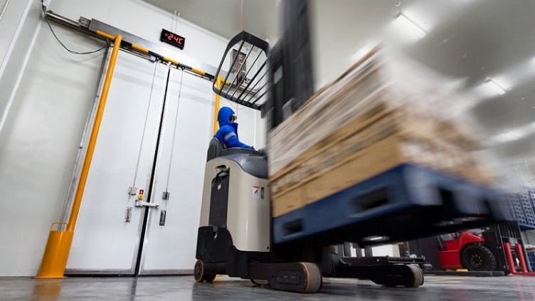 Blurred view of worker using machine to lift the stocks in the warehouse