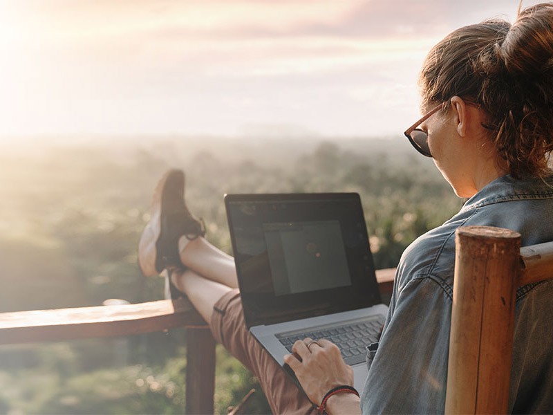 A woman using a laptop in the balcony with a view