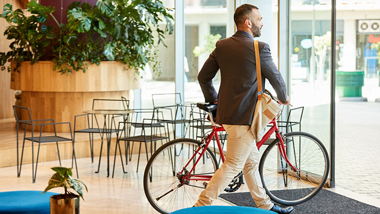 Homme sortant d'un immeuble de bureau avec son vélo