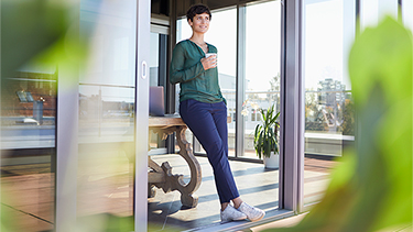 Smiling businesswoman leaning against table having a coffee break