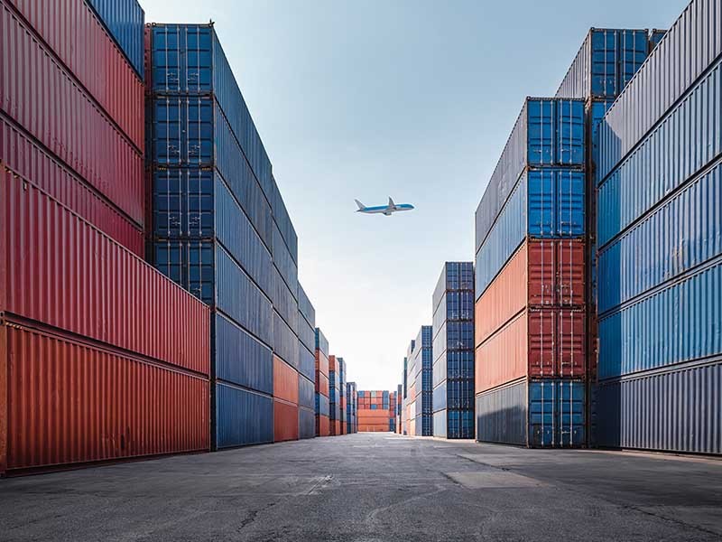 A plane above a port with containers