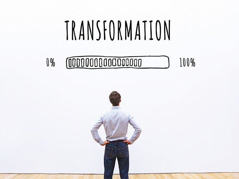 A corporate man watching the progress of a loading bar titled transformation