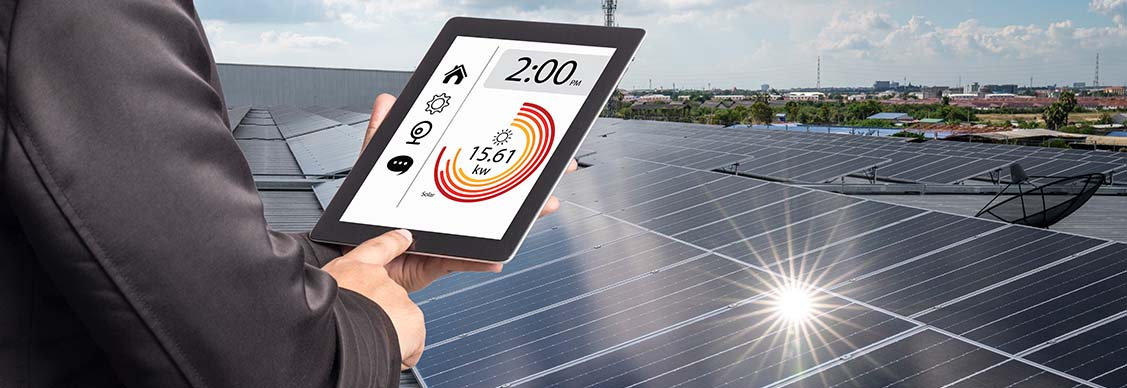 Man examining generation of solar power plant, holding digital tablet with a chart of electricity production.