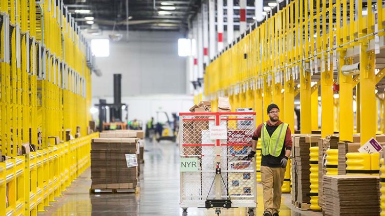 Ouvrier logistique déplaçant le chariot à cartouches dans l'entrepôt