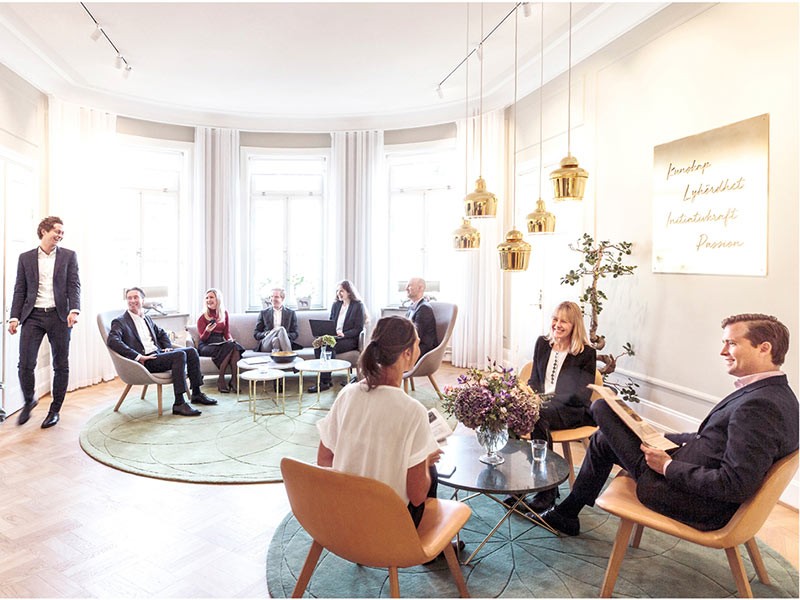 Employees sitting and interacting in office common area at workplace.