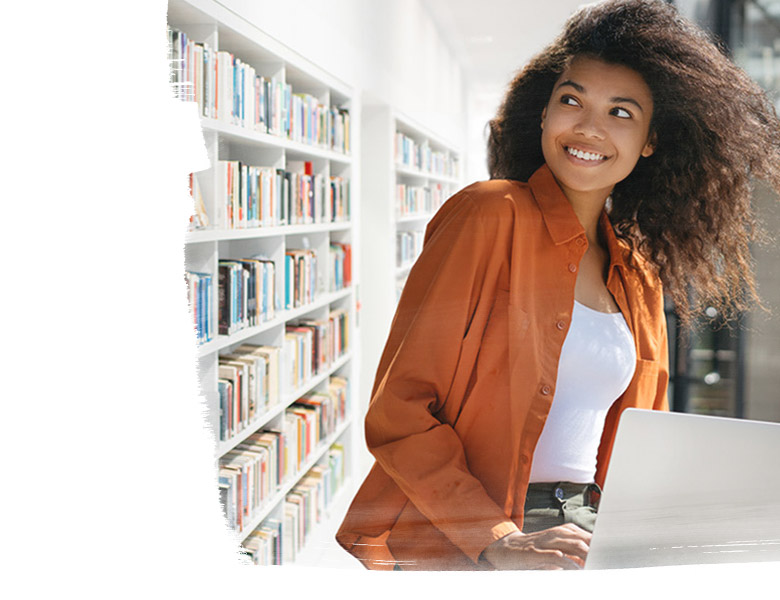 Young girl working on a computer with a shelf of books behind her